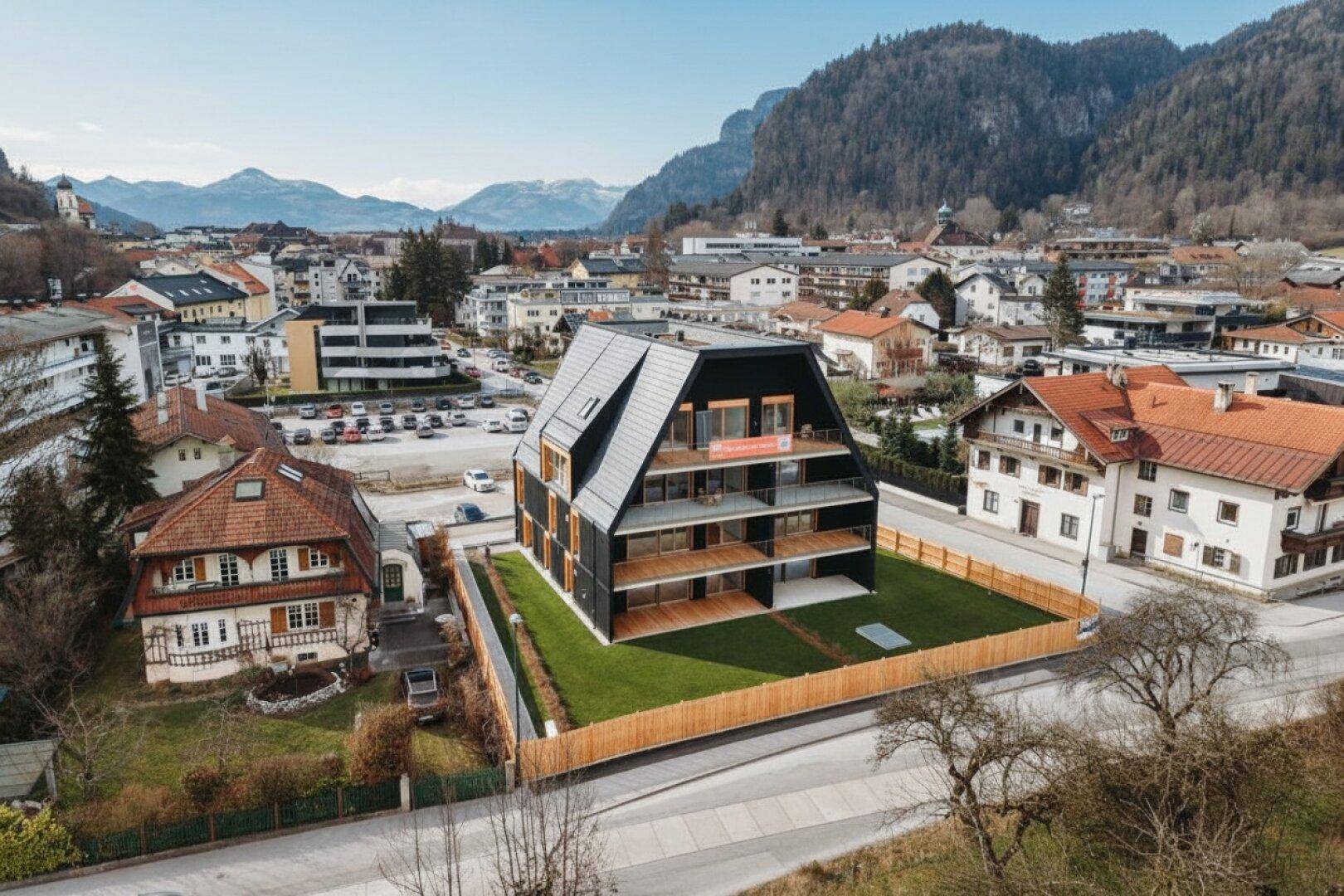 Architektonisch ansprechendes Neubauprojekt mit Balkonen und Blick auf die umliegende Berglandschaft.