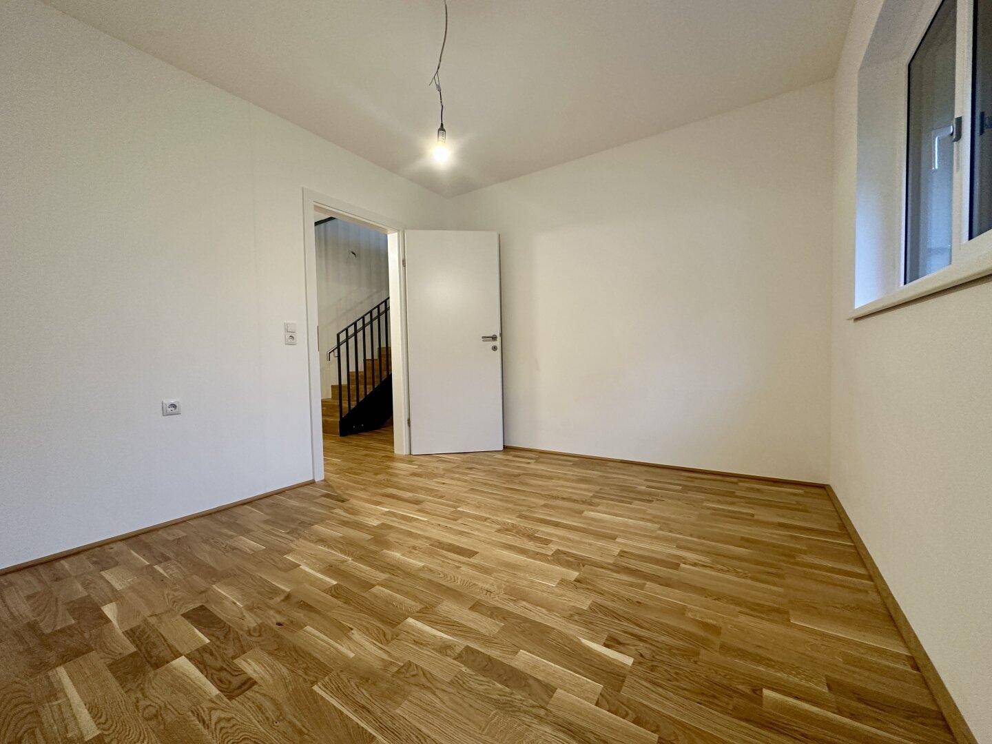 Schlafzimmer mit Parkettboden und Zugang zu einem weiteren Raum oder Flur.