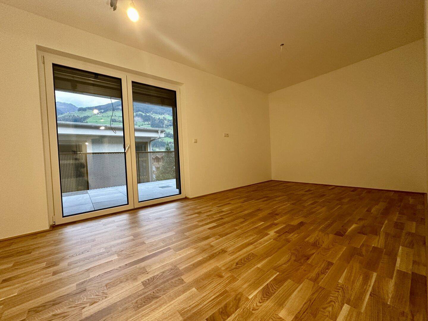 Schlafzimmer mit Parkettboden und Zugang zu einem Balkon oder einer Terrasse.