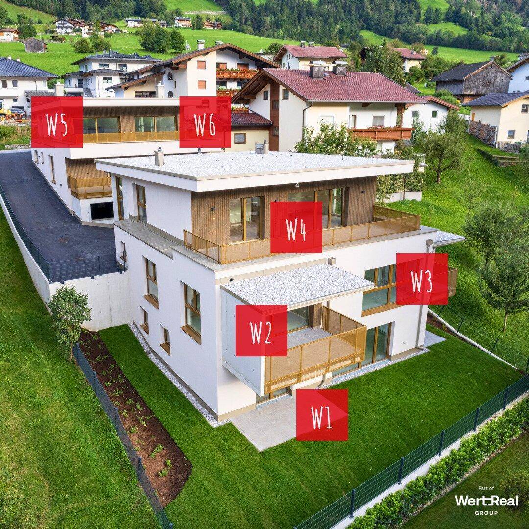 Luftaufnahme eines modernen Wohngebäudes mit mehreren Wohneinheiten und Grünflächen.