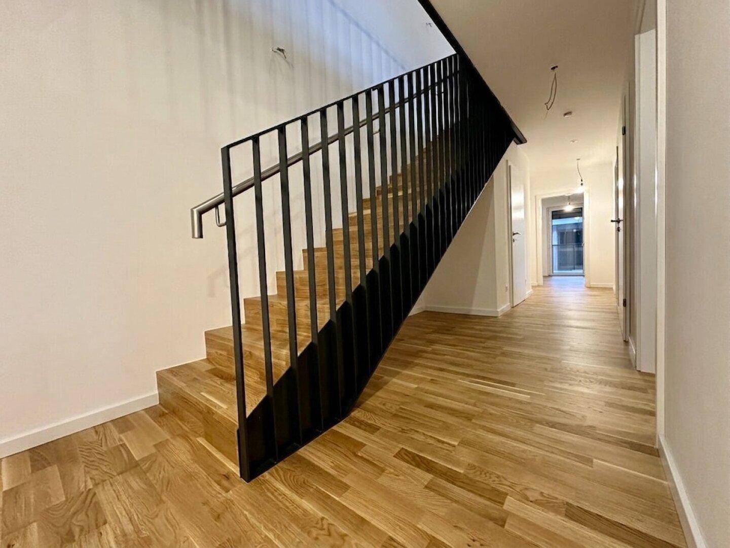 Moderner Flur mit Holztreppe und Parkettboden, der die verschiedenen Ebenen verbindet.