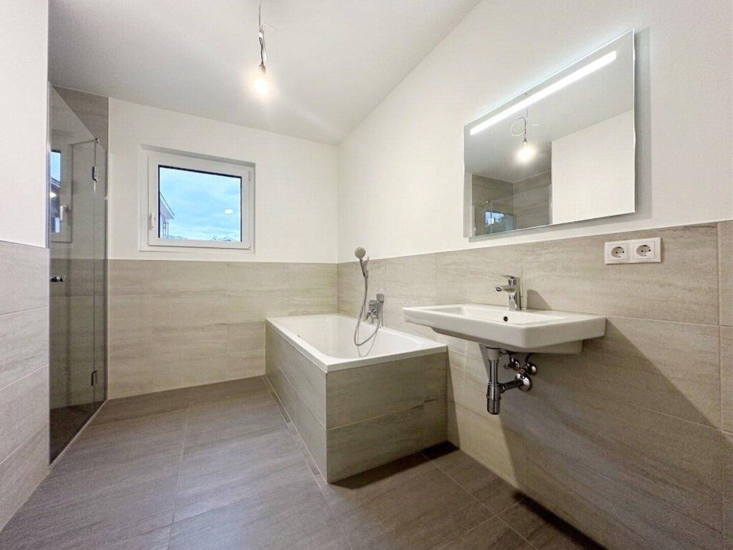 Modernes Badezimmer mit Badewanne, Dusche, Einzelwaschbecken und Fenster.