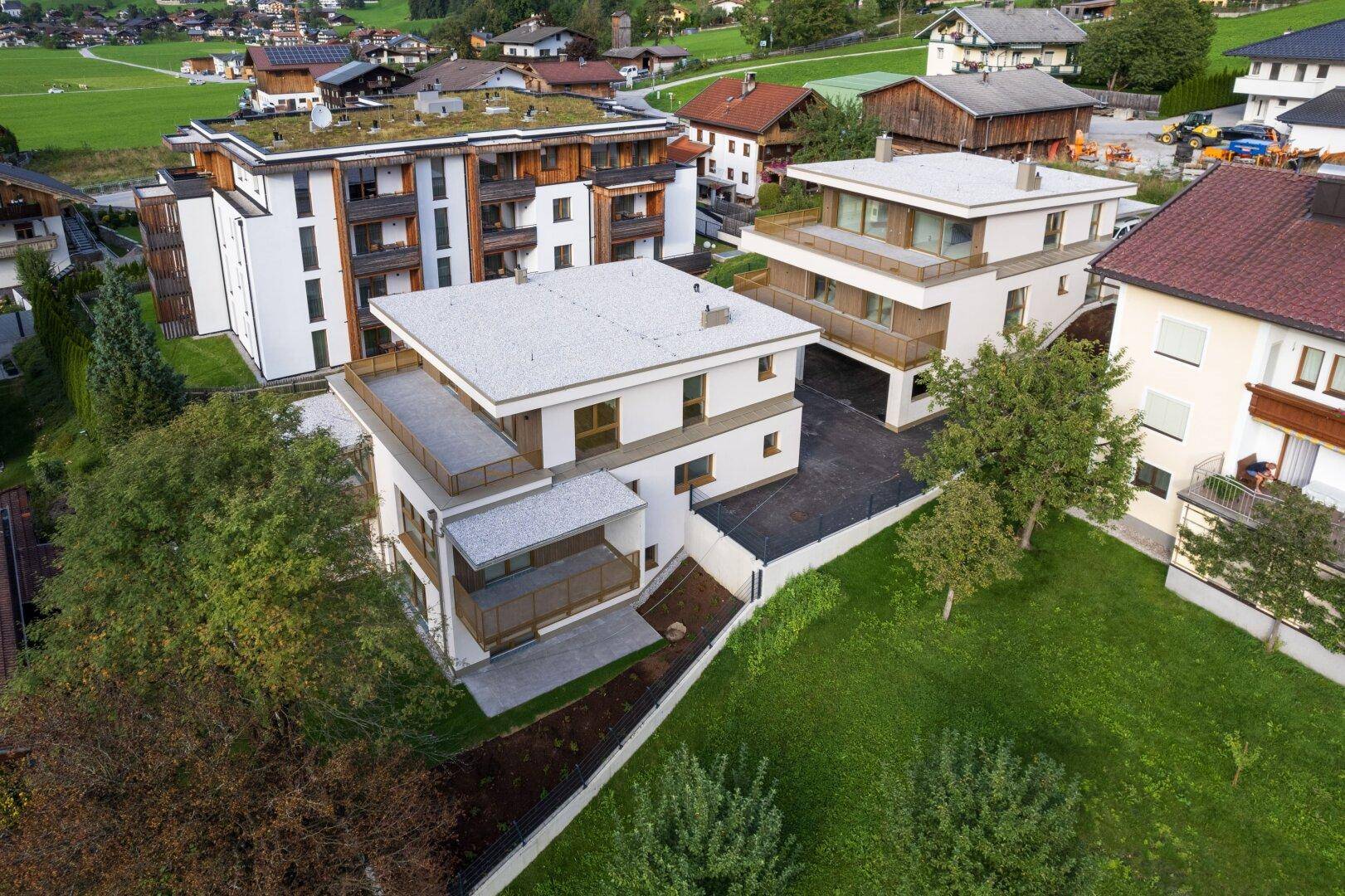 Luftaufnahme eines modernen Wohnkomplexes in grüner Umgebung mit Flachdächern.