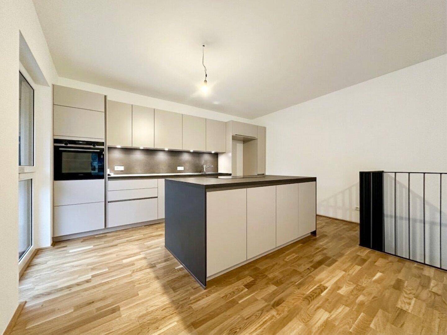 Moderne Einbauküche mit Kücheninsel, integrierten Geräten und hellem Parkettboden.