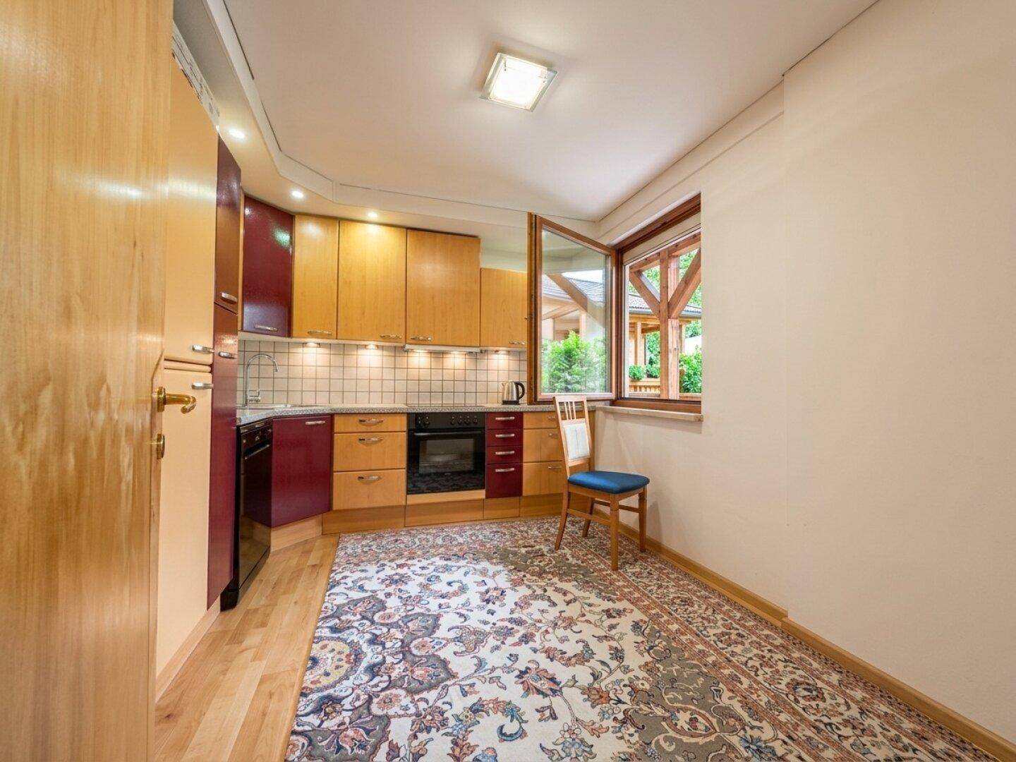 Funktionale Küche mit Holz- und roten Fronten, Einbaugeräten und Teppich.