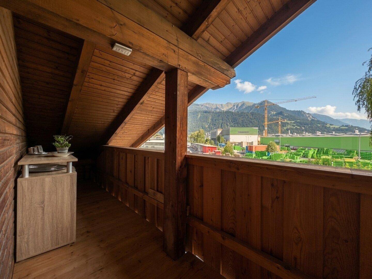 Überdachter Holzbalkon mit Bergblick und Blick auf die umliegende Landschaft.