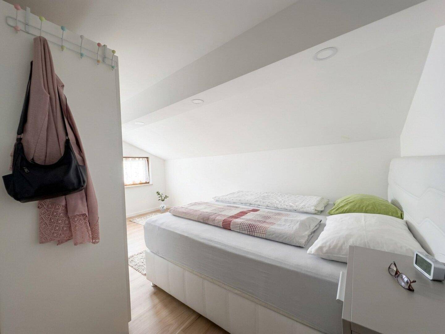 Gemütliches Schlafzimmer im Dachgeschoss mit schrägen Wänden und Holzboden.