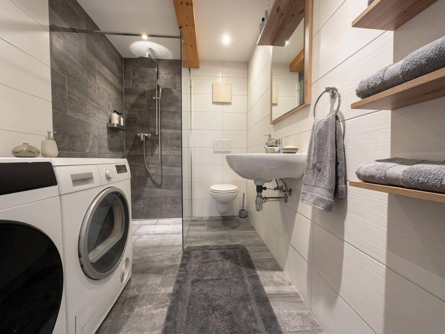 Modernes Badezimmer mit begehbarer Dusche, WC, Waschbecken und Waschmaschine.