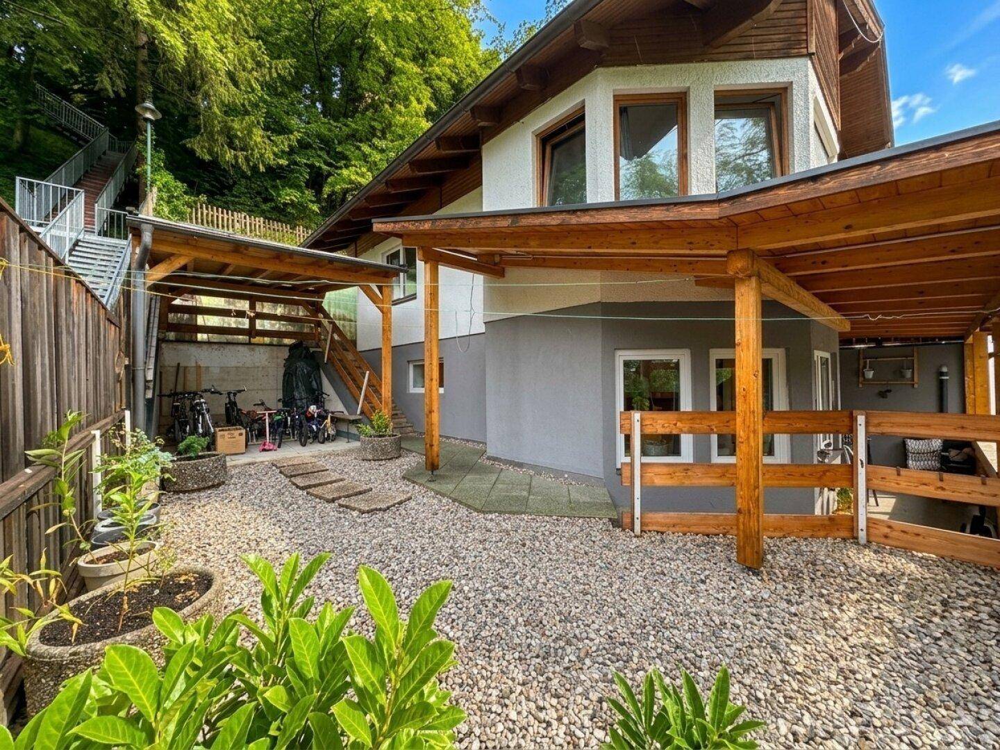 Kiesgartenbereich mit Pflanzenkübeln, überdachtem Unterstand und Zugang zum Haus.