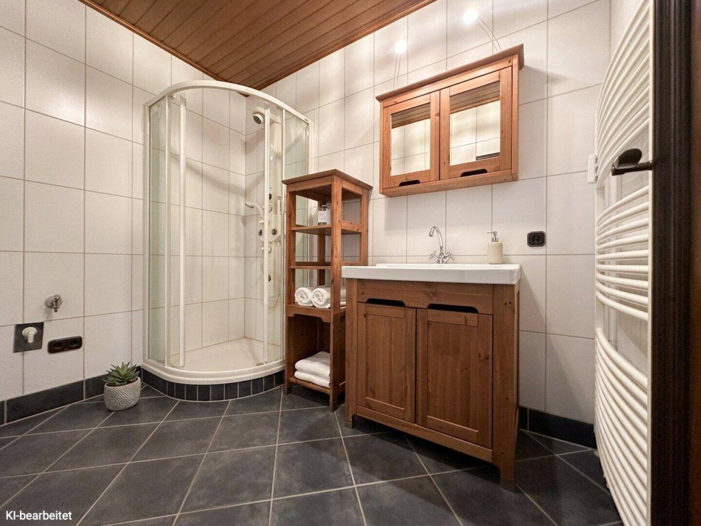 Funktionales Badezimmer mit Duschkabine, Holzwaschtisch und dunklen Bodenfliesen.