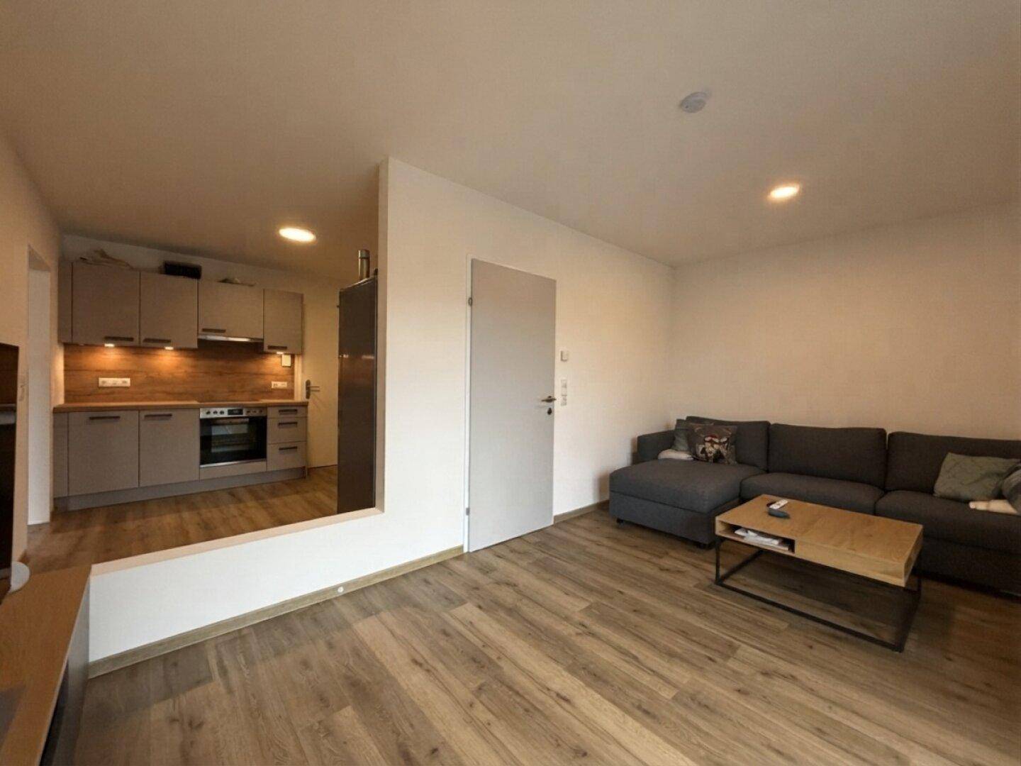 Gemütlicher Wohnbereich mit Sofa und Couchtisch, angrenzend an eine moderne Küche.