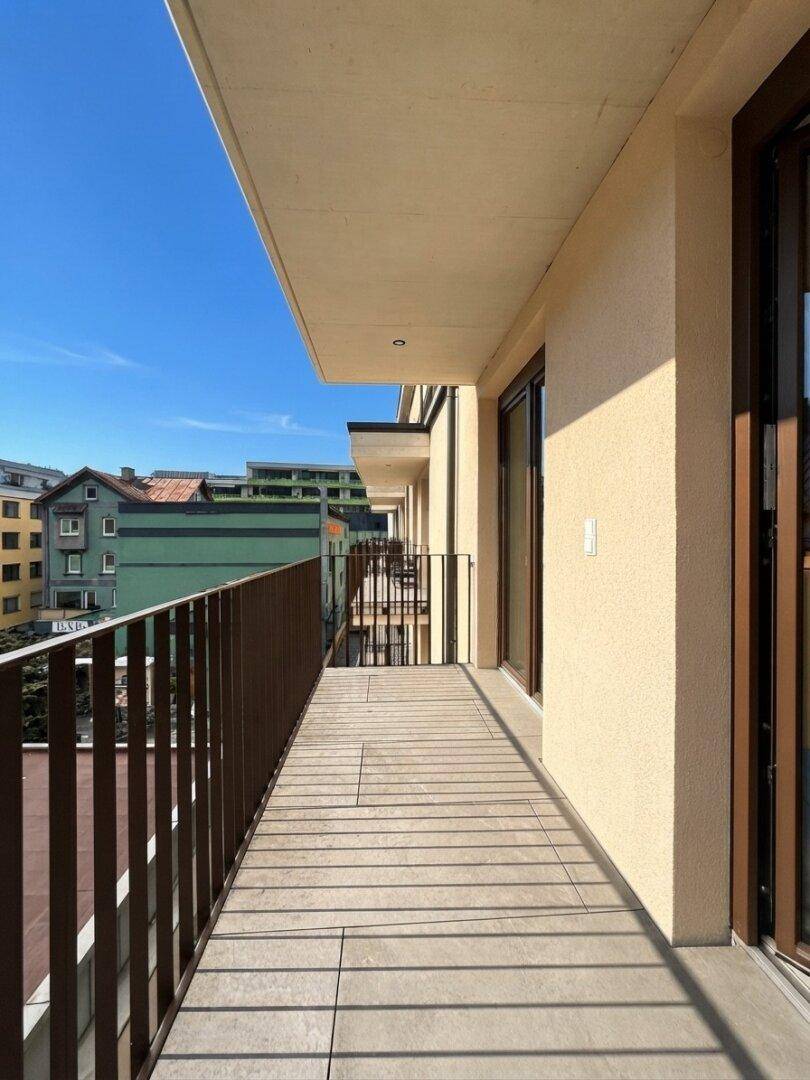 Langer Balkon mit Fliesenboden und Metallgeländer, bietet Platz für Outdoor-Möbel.