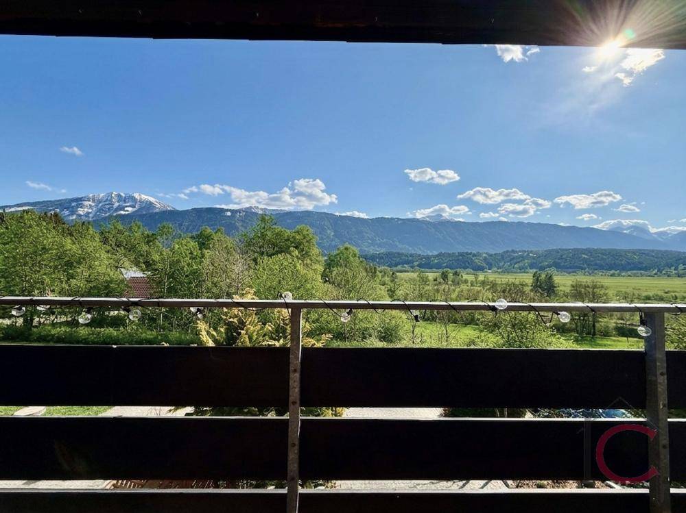 Sonniger Balkon mit weitem Blick über die grüne Landschaft und schneebedeckte Berge.