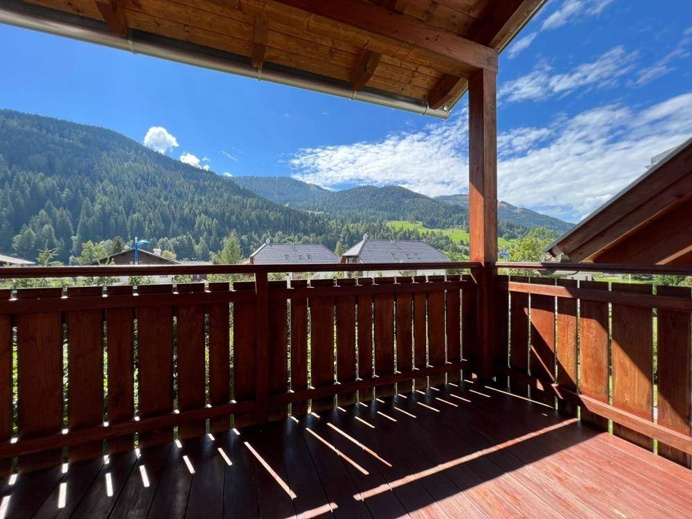 Geräumiger Holzbalkon mit Panoramablick auf die Alpen und viel Sonnenschein.