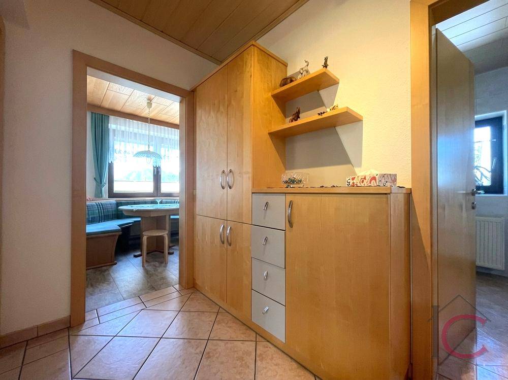 Flur mit praktischen Holzschränken und Blick in einen gemütlichen Essbereich.
