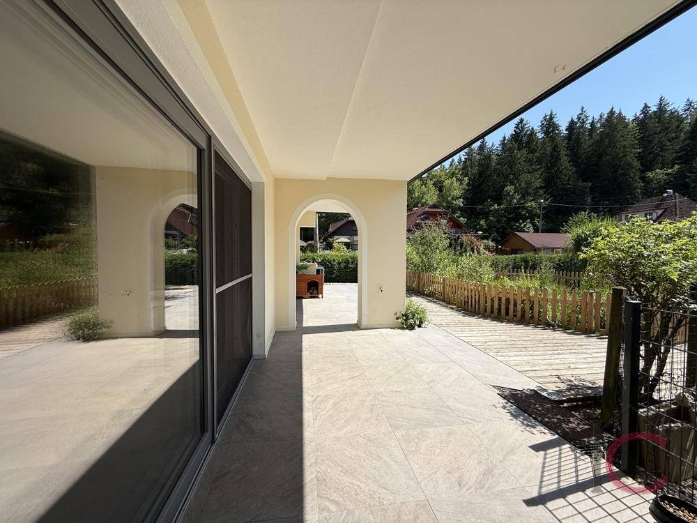 Helle überdachte Terrasse mit großen Schiebetüren, die einen weiten Blick ins Grüne ermöglichen.
