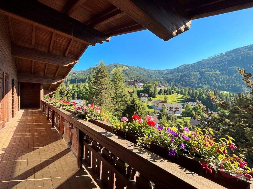 Breiter Balkon mit Blumenkästen und Panoramablick auf die grüne Berglandschaft.