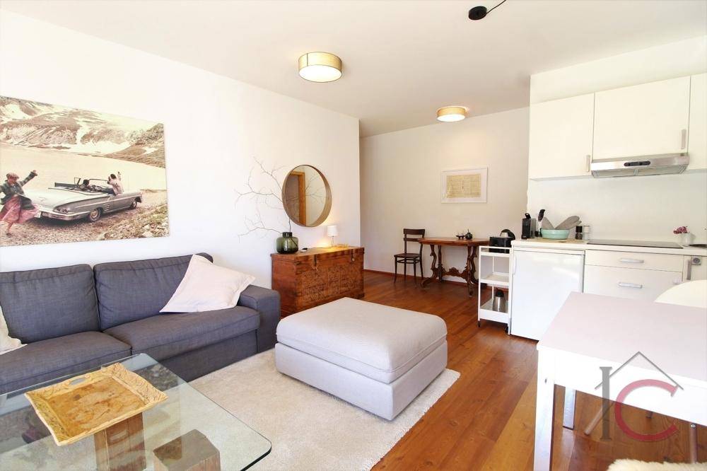 Heller Wohnbereich mit Sofa, Esstisch und kleiner Küchenzeile, ideal für kompaktes Wohnen.