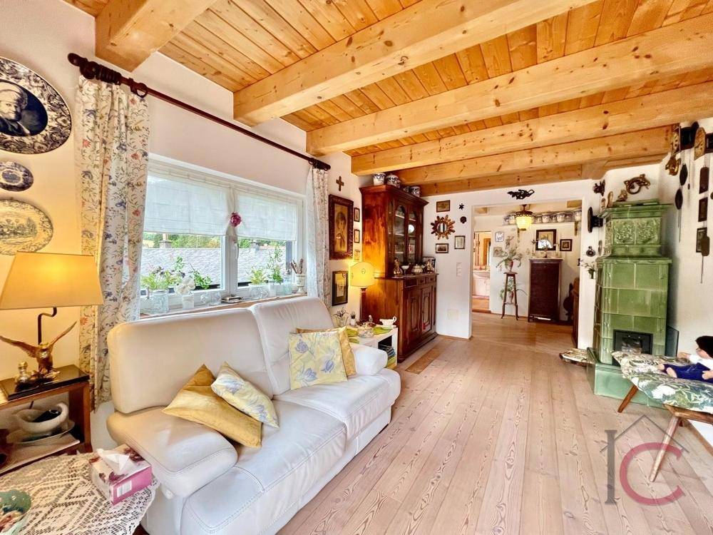 Heller Wohnraum mit Holzboden, weißem Sofa und Blick ins Grüne.