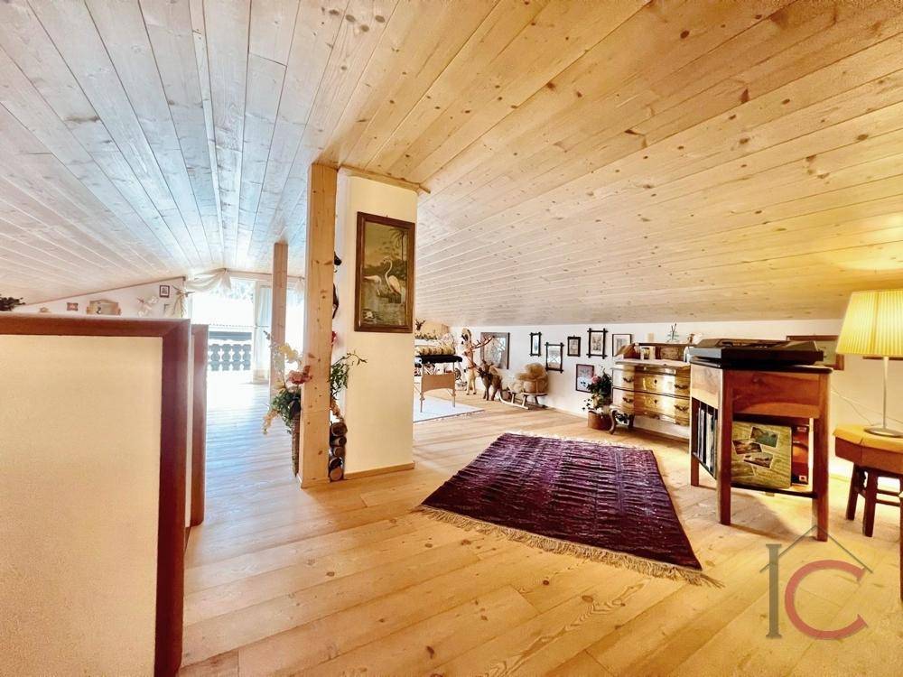 Offener Dachbodenbereich mit Holzboden, Holzbalkendecke und traditionellen Möbeln.