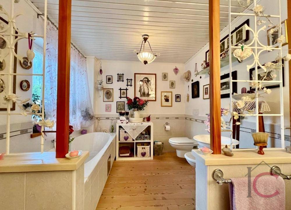 Helles Badezimmer mit Badewanne, WC und traditioneller Dekoration.