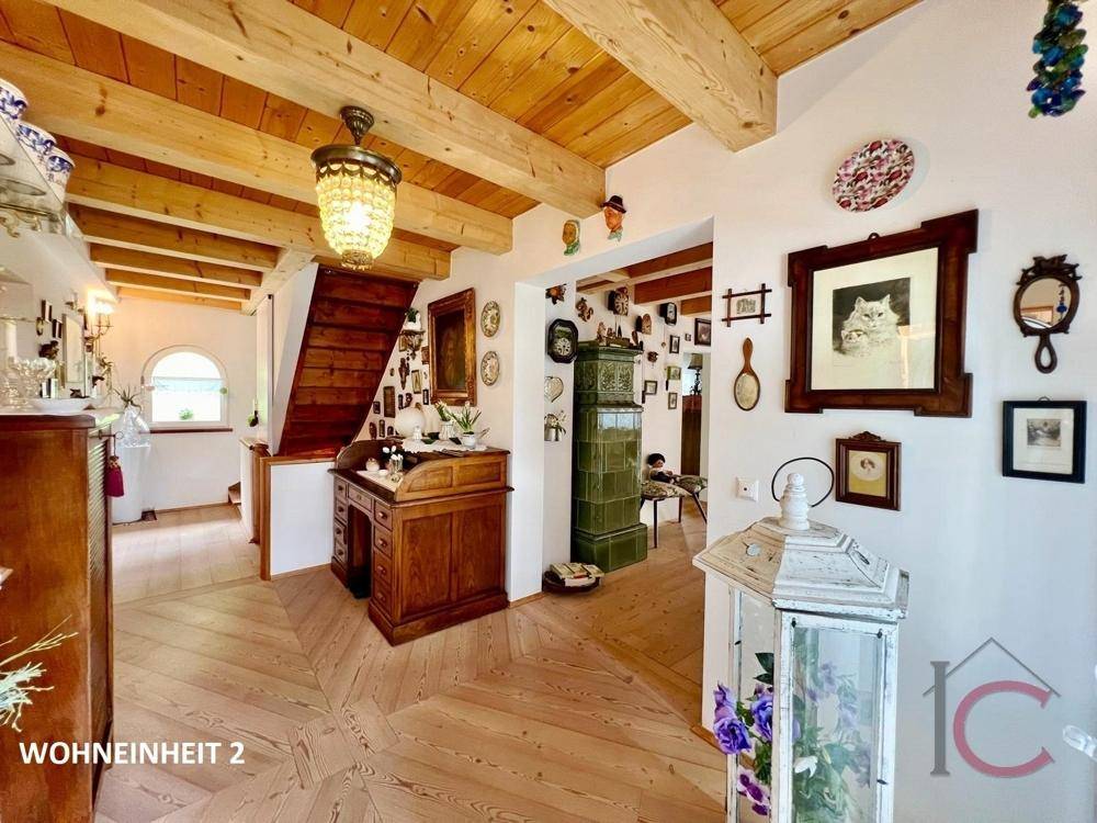 Geräumiger Flur mit Holzboden, traditionellem Kachelofen und Treppenaufgang.