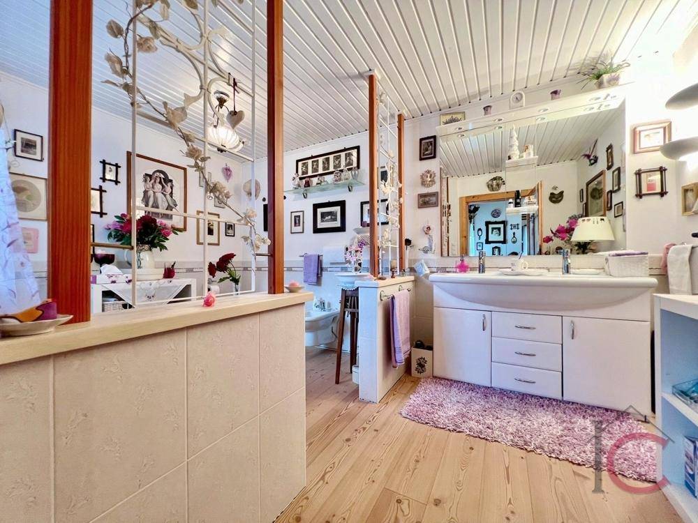 Badezimmer mit Doppelwaschbecken, Holzboden und Spiegel.