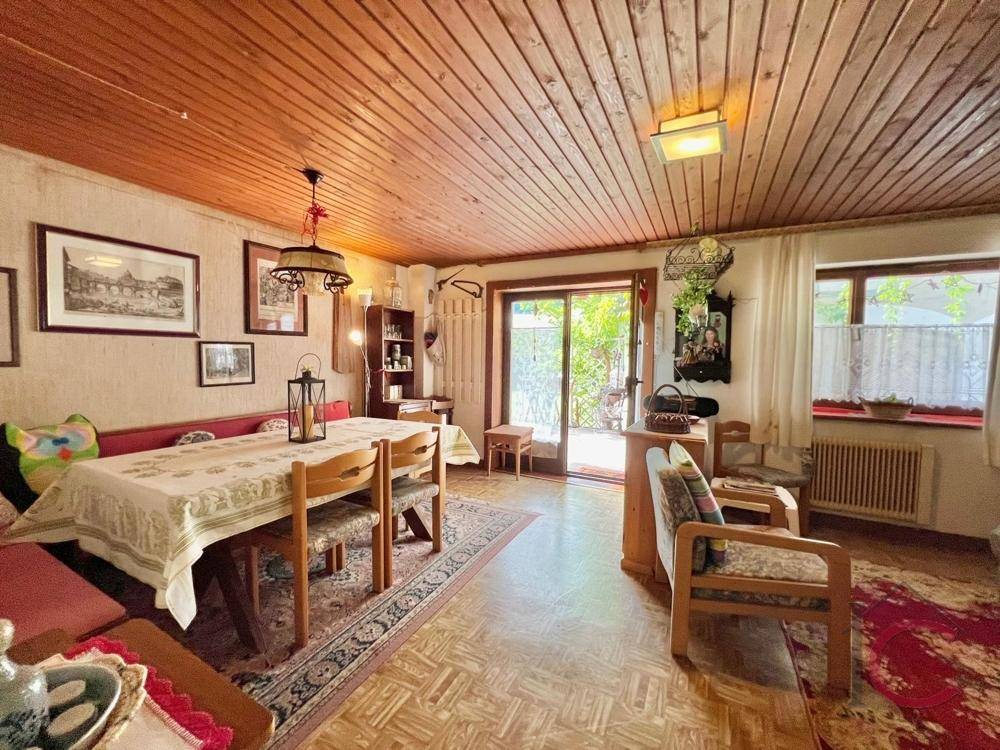 Gemütlicher Wohn-Essbereich mit Holztäfelung an Decke und Wänden, sowie Zugang zur Terrasse.