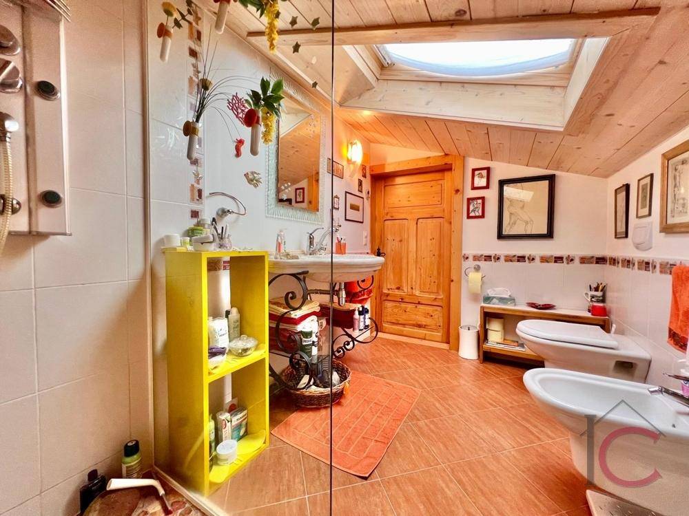Badezimmer im Dachgeschoss mit Fliesenboden, Dachfenster und traditioneller Einrichtung.