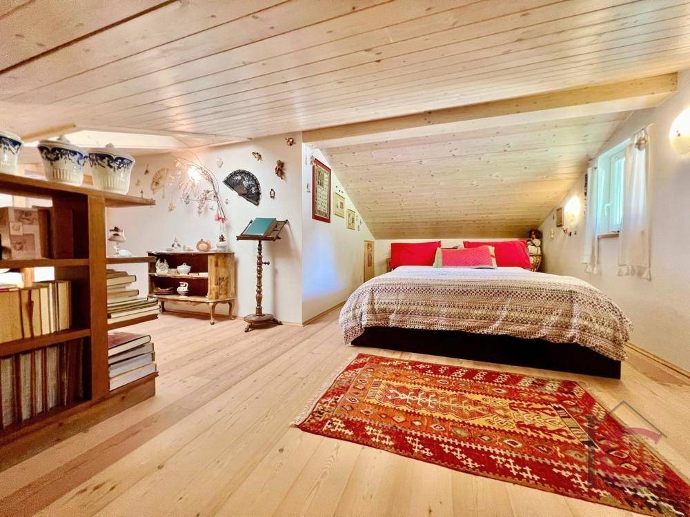 Gemütliches Schlafzimmer im Dachgeschoss mit Holzboden und schrägen Wänden.