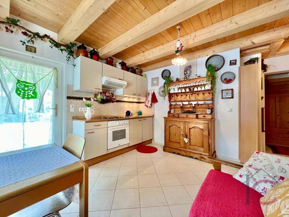 Gemütliche Küche mit traditionellem Holzschrank, Fliesenboden und Zugang nach draußen.