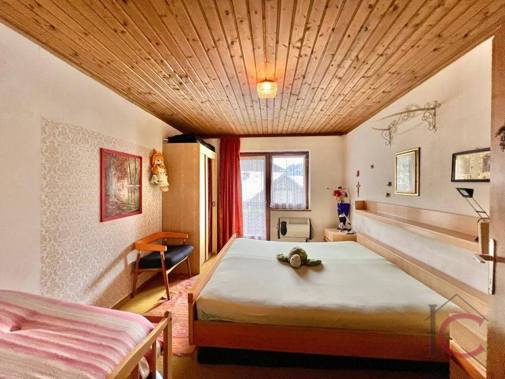 Schlafzimmer mit Holztäfelung an der Decke und einem Doppelbett, einfach und funktional eingerichtet.