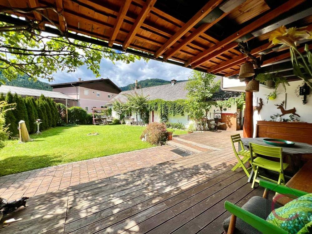 Große Terrasse mit Holzdeck, Sitzgelegenheiten und Blick auf den Garten und die Berge.