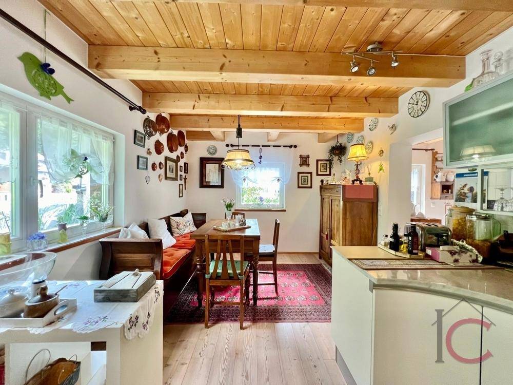 Gemütlicher Wohn-Essbereich mit Holzbalkendecke, traditionellen Möbeln und offener Küche.
