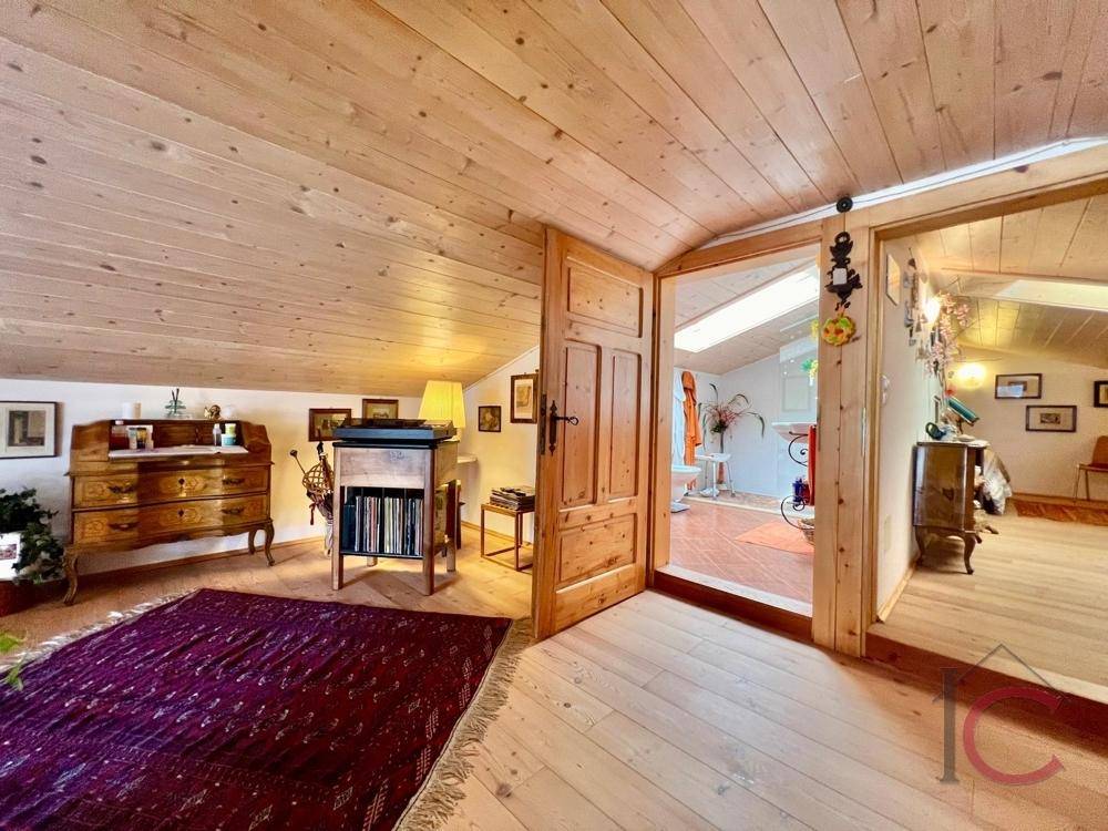 Heller Dachbodenbereich mit Holzboden, Holztüren und Zugang zu weiteren Räumen.