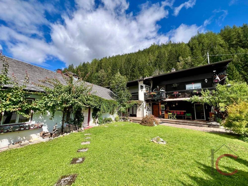 Weitläufiger Gartenbereich mit Rasenfläche und Blick auf die umliegende Berglandschaft.