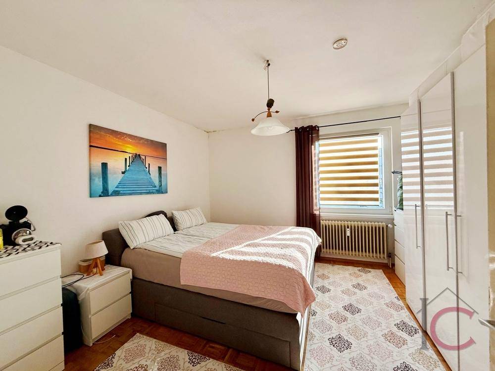 Helles Schlafzimmer mit Doppelbett, Nachttischen und großem Kleiderschrank.