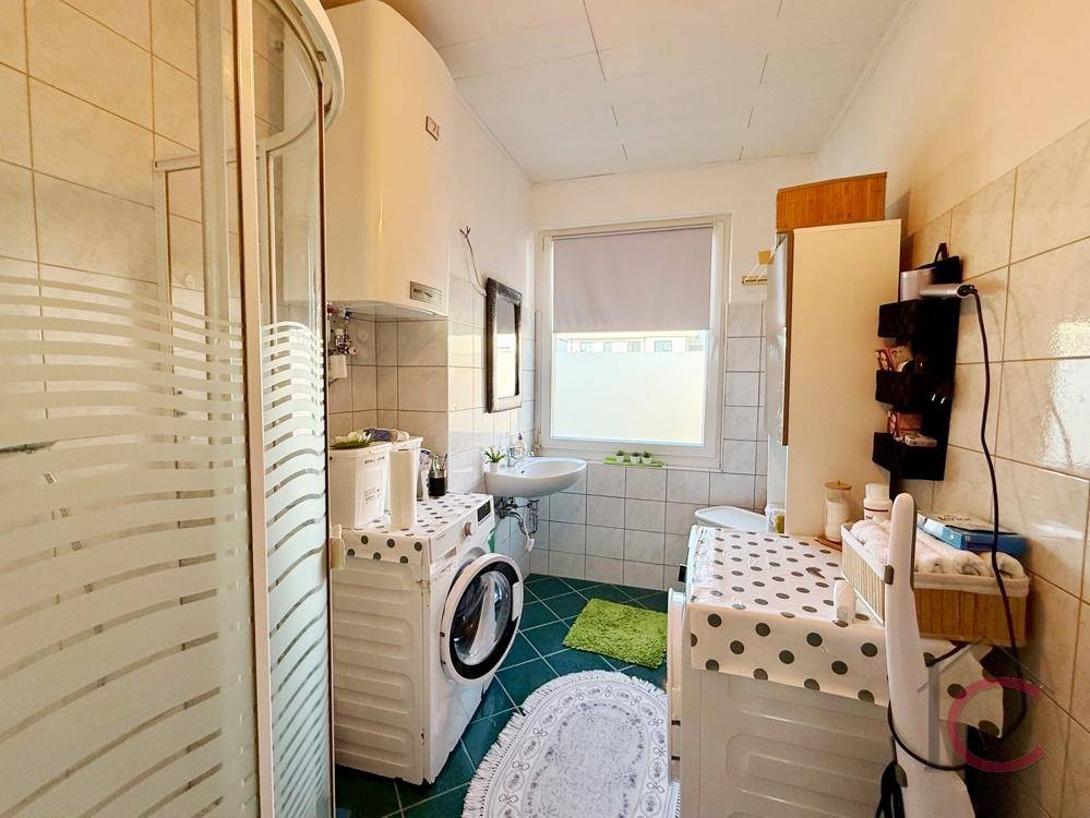 Badezimmer mit Duschkabine, Waschbecken, Toilette und Waschmaschine.
