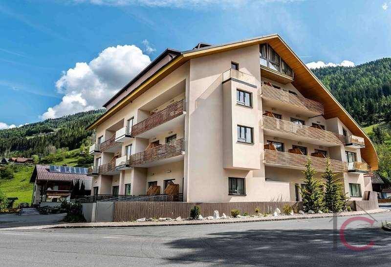 Moderne Gebäudefassade mit zahlreichen Balkonen und alpiner Architektur.