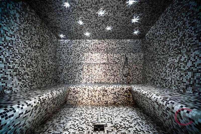Dampfbad mit glitzernden Mosaikfliesen und integrierten Sitzbänken für Erholung.