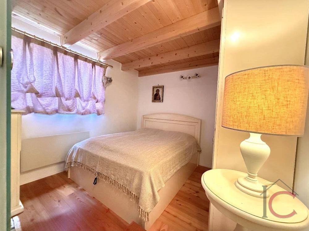 Gemütliches Schlafzimmer mit Holzbalkendecke, Doppelbett und natürlichem Lichteinfall.