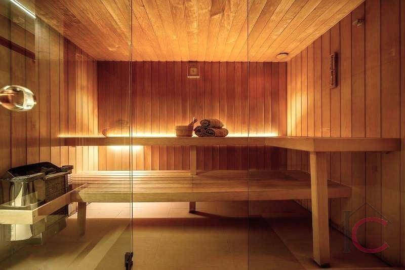 Innenansicht einer holzvertäfelten Sauna mit Bänken und stimmungsvoller Beleuchtung.