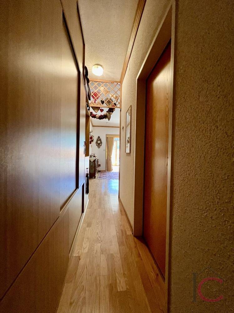Langer Flur mit Holzwänden und Holzboden, der zu weiteren Räumen führt.