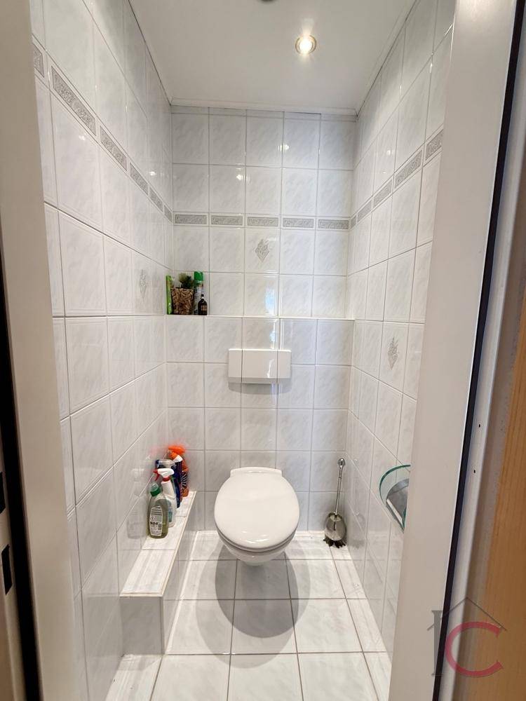 Separates WC mit Wand-WC und hellen Fliesen, praktisch und pflegeleicht.
