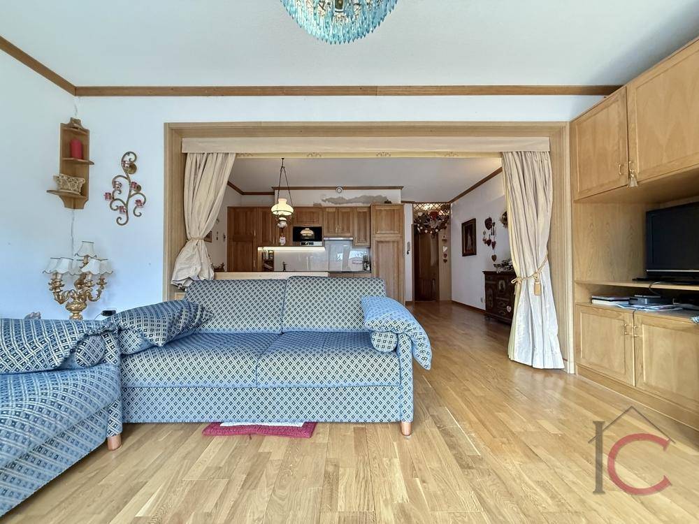Heller Wohnbereich mit Holzboden und offenem Übergang zur Küche, ideal für ein geselliges Beisammensein.