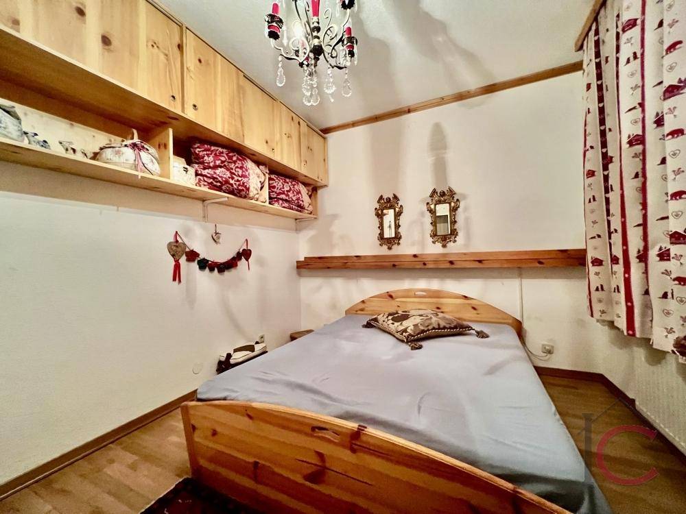 Gemütliches Schlafzimmer mit viel Holz, einem bequemen Bett und praktischen Ablageflächen.