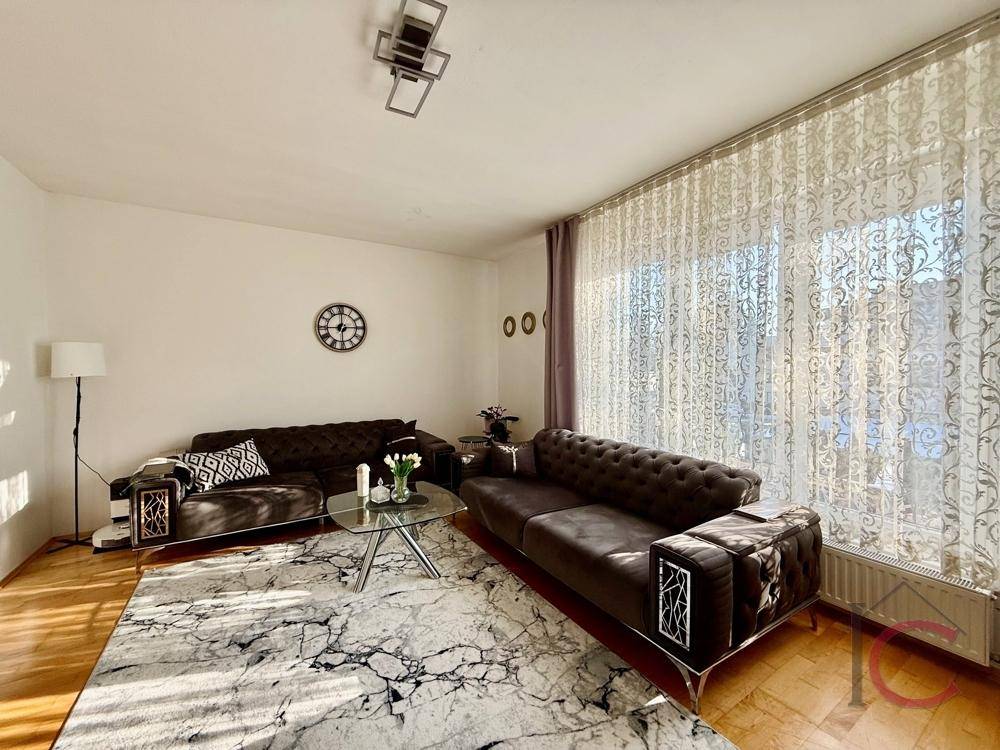 Gemütliches Wohnzimmer mit zwei Sofas, Couchtisch und viel Tageslicht durch große Fenster.