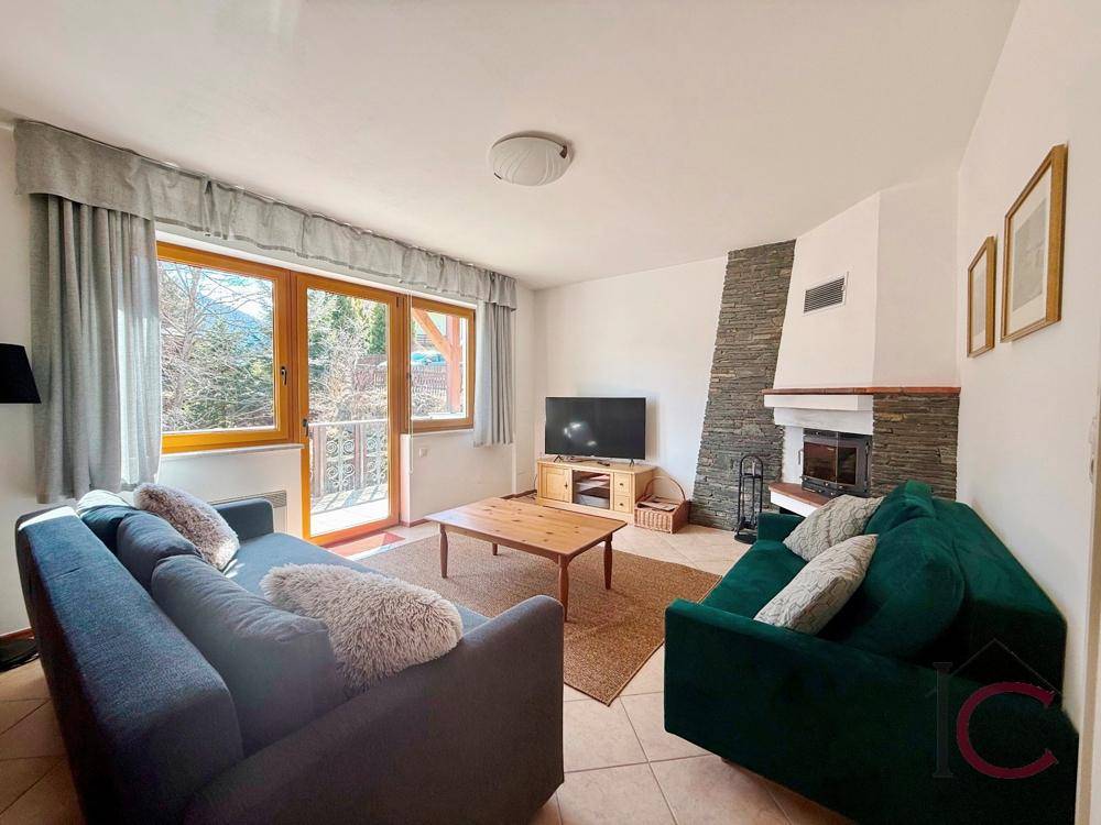 Helles Wohnzimmer mit Kamin, bequemen Sofas und Zugang zu einem Balkon.