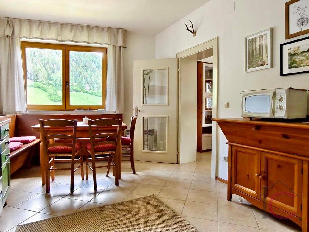 Gemütliche Küche mit Essbereich, grünen Schränken und einem Fenster mit Bergblick.