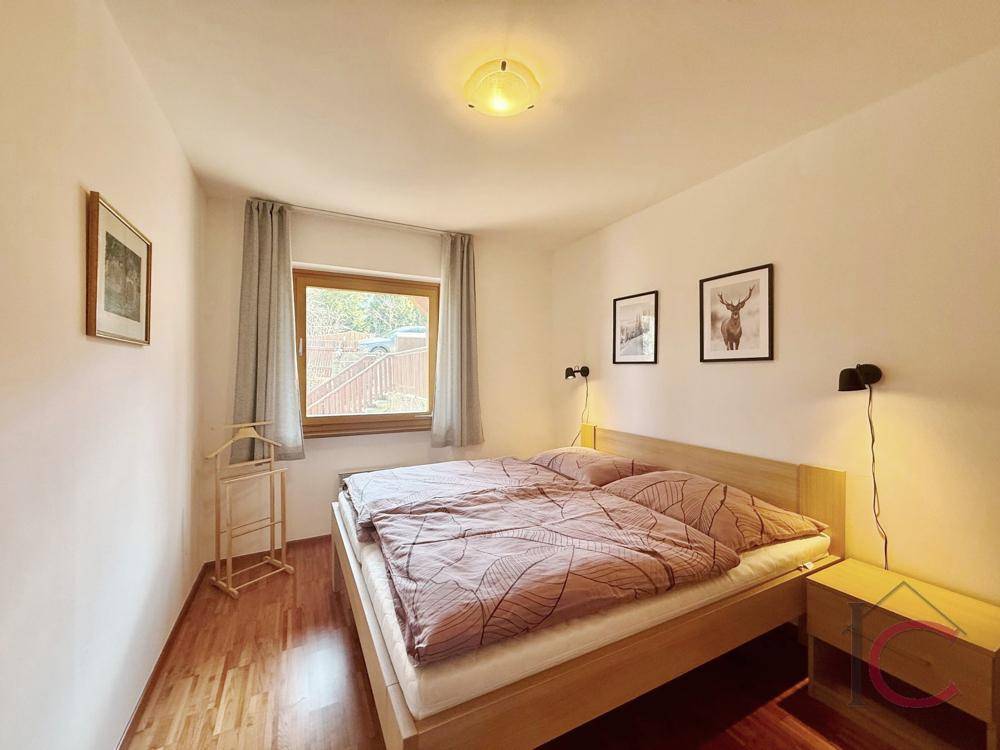 Schlafzimmer mit Doppelbett, Holzboden und Fenster mit Blick auf die Umgebung.